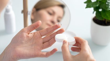 A woman holds a contact lens on her finger