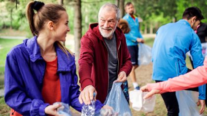 A roup of fit young people picking up litter in nature, a plogging concept.