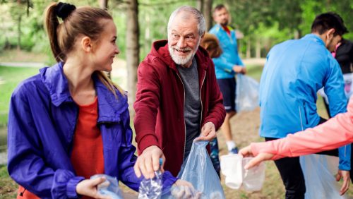 A roup of fit young people picking up litter in nature, a plogging concept.